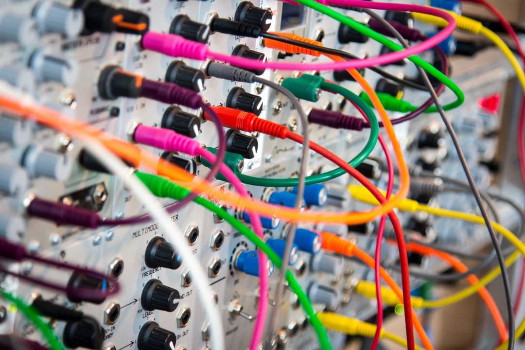 Tangled colorful network patch cables on a synth-style patch panel