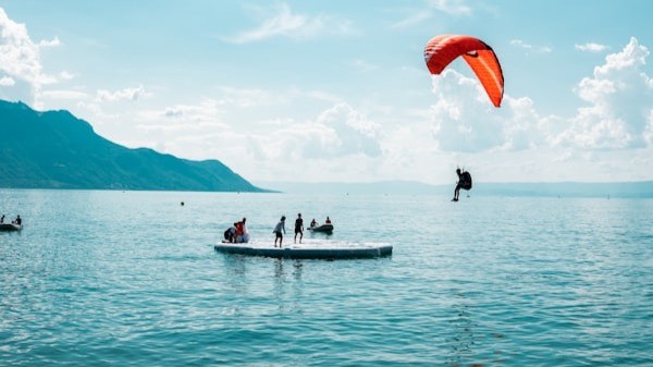 People on a floating platform on a mountain lake with a kite-surfer landing above them - a literal landing zone