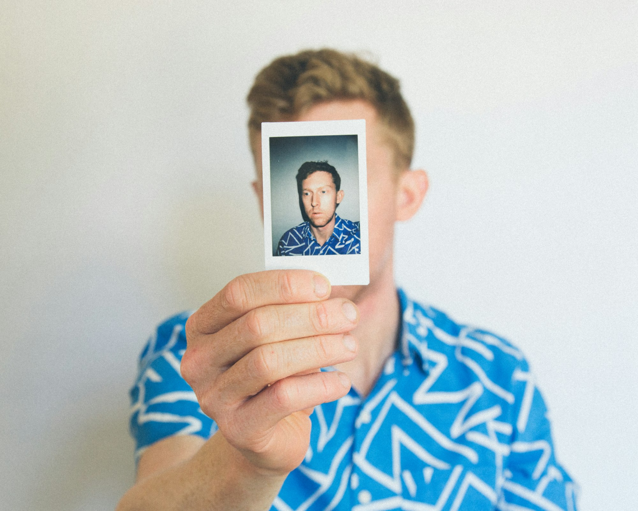 Person holding a polaroid photo in front of their face - representing identity