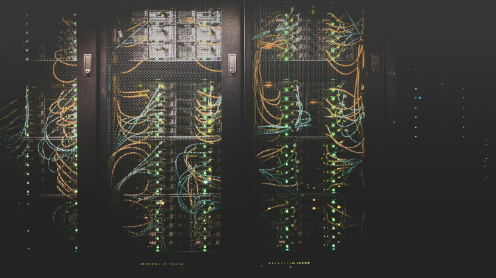 Server rack lit up with dense fibre-optic cabling