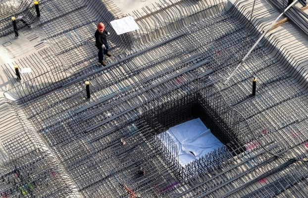 Construction workers on a reinforced concrete rebar grid viewed from above