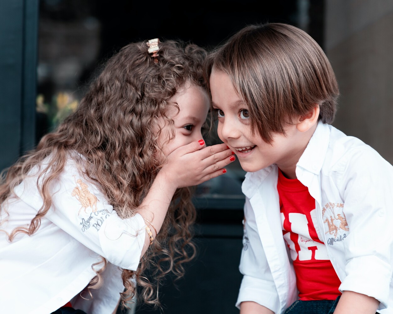 Two children whispering a secret to each other