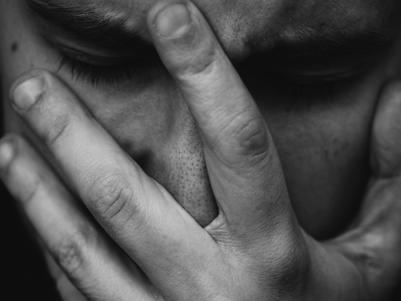 Person with head in hands in distress, black and white
