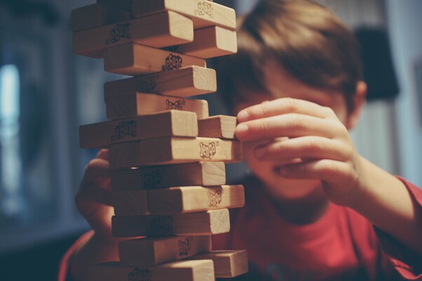 Child carefully playing Jenga, illustrating precarious balance