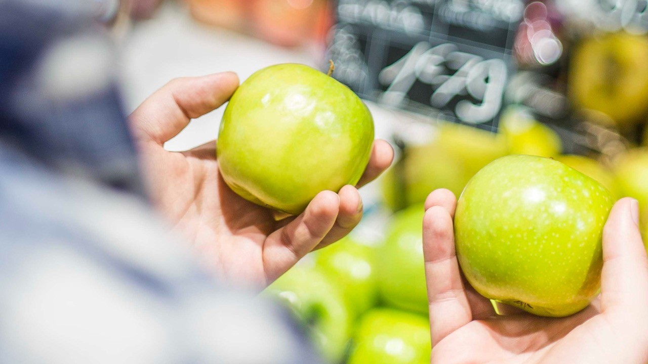 Two hands each holding a green apple - comparing apples to apples, not apples to oranges