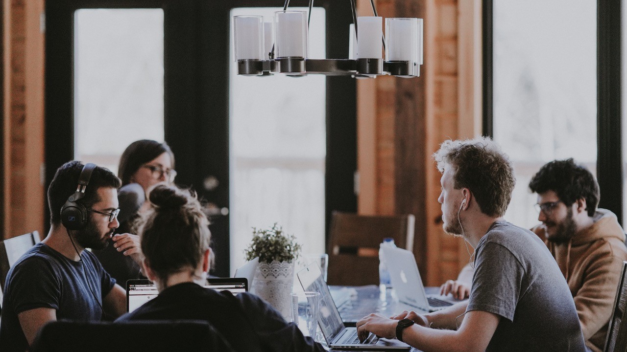 A cross-functional team working together around a table with laptops